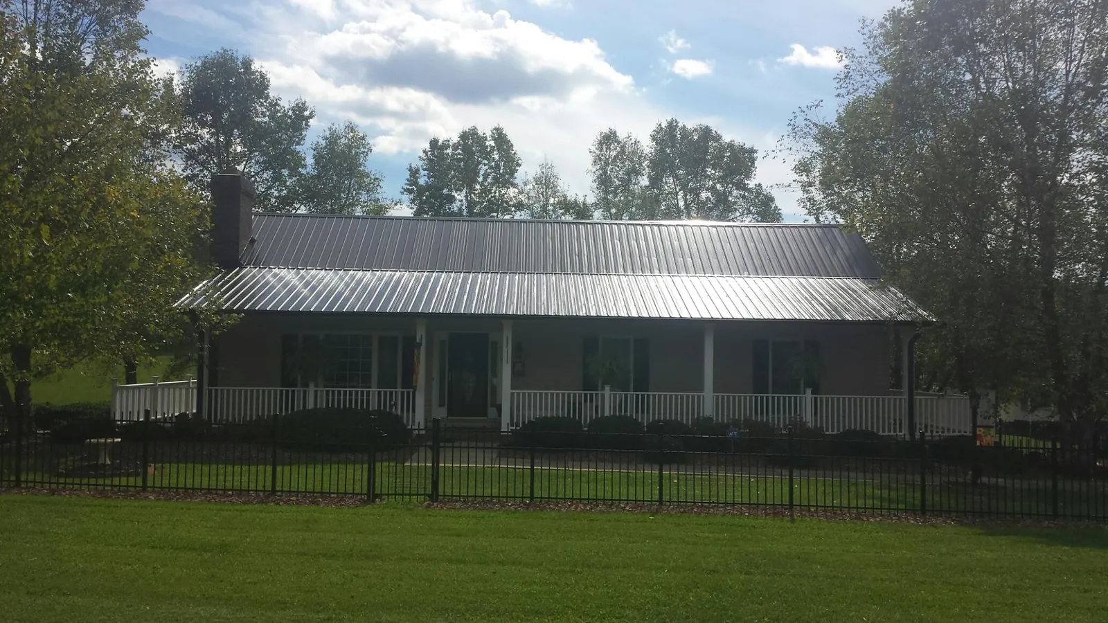 Gray metal roof on a brick ranch with a full width front porch — Gutter Guard Installation work by our crew in Shiloh