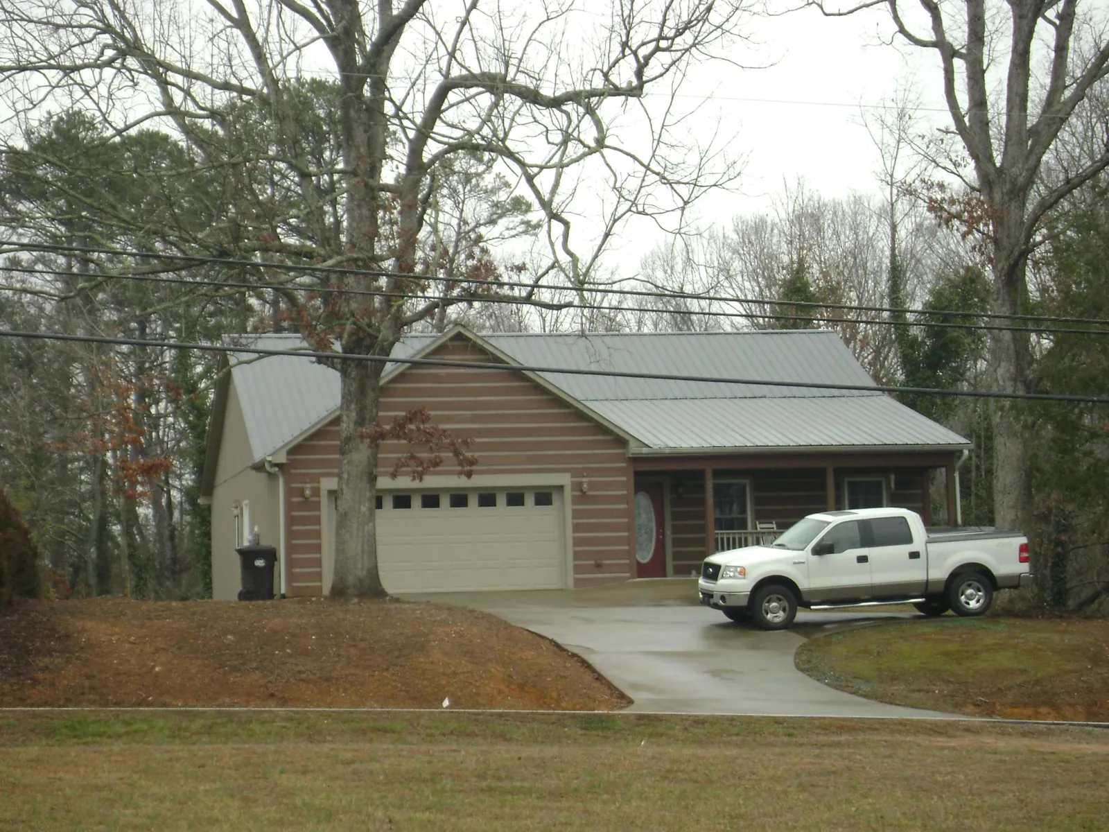 Gray metal roof on a log sided house with an attached two car garage in Shiloh